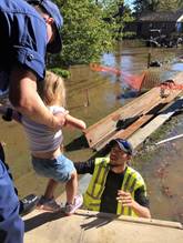 A local fire department rescue worker prepares to help Petty Officer 1st Class James Prosser bring his daughter, 2-year-old Annalynne, to safety in Lumberton, North Carolina, Oct. 10, 2016. The town experienced catastrophic flooding requiring evacuations for many residents. (U.S. Coast Guard photo by Master Chief Petty Officer Louis Coleman/Released)