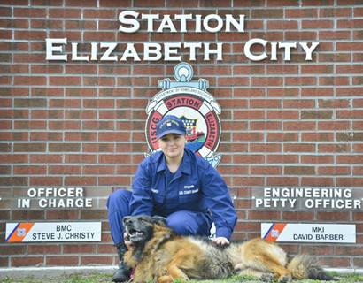 Seaman Nina Bowen and Chief Bert, the Station Elizabeth City, North Carolina, mascot, pose for a portrait in front of the station Feb. 14, 2017. Bowen is one of Bert's primary caretakers at the station. (U.S. Coast Guard photo by Petty Officer 2nd Class Nate Littlejohn)